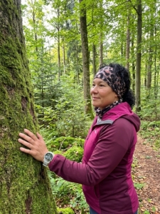 Therapeutin mit einer Hand am Baum beim Waldbaden